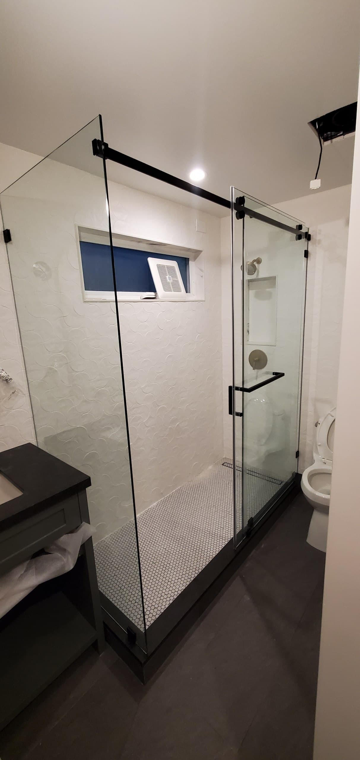 Black matte sliding shower enclosure over a penny-tile floor