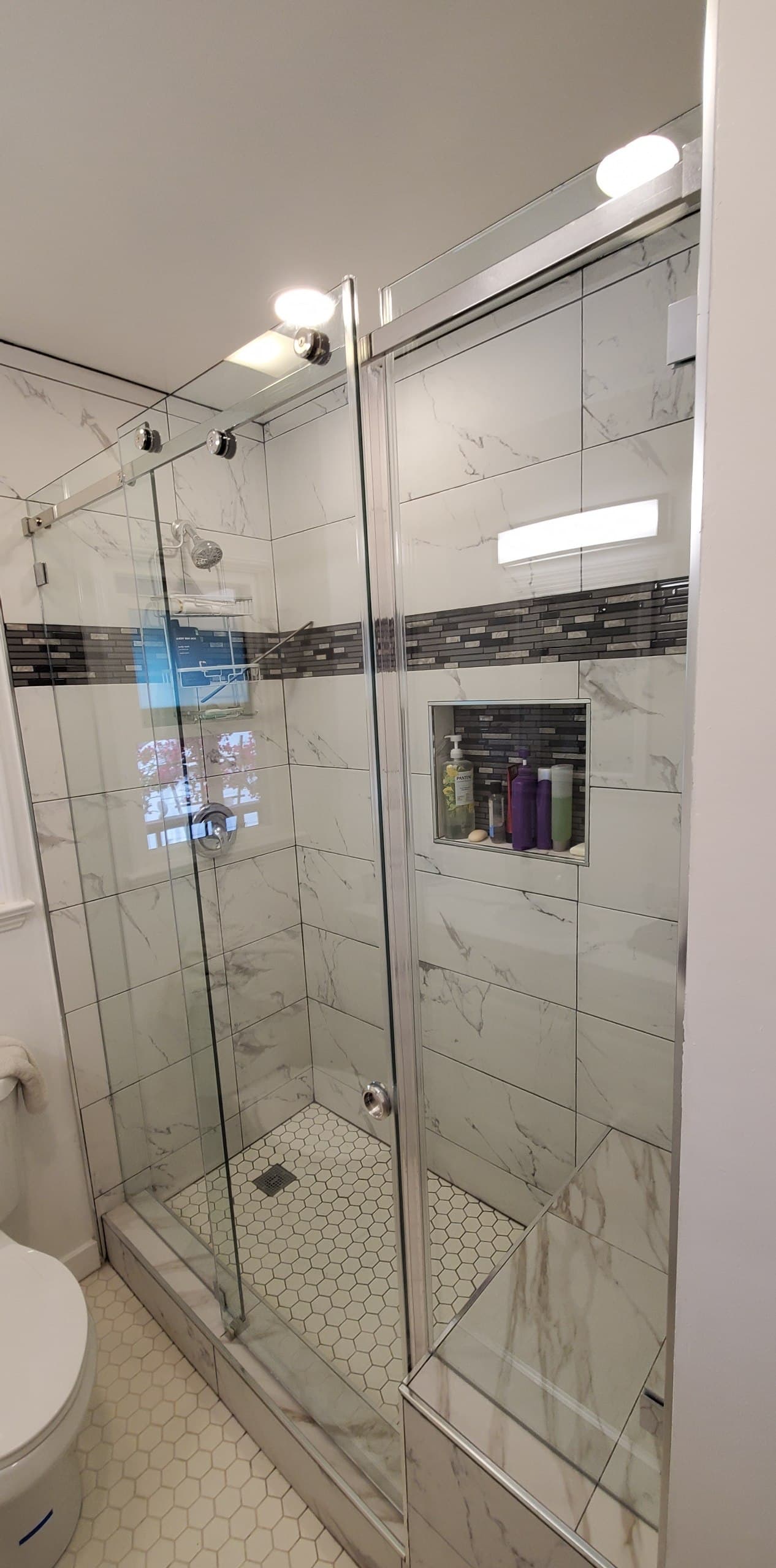 Chrome sliding shower enclosure with a glass mosaic accent band