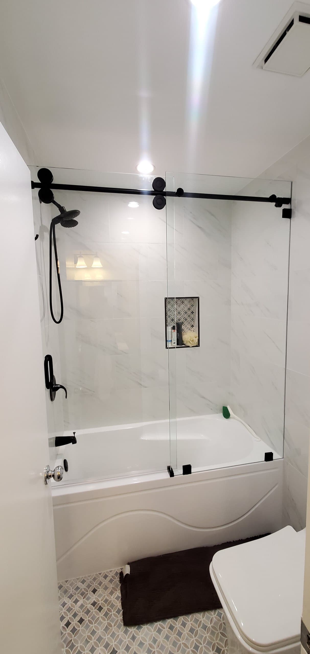 Sliding glass tub enclosure on black barn-door hardware