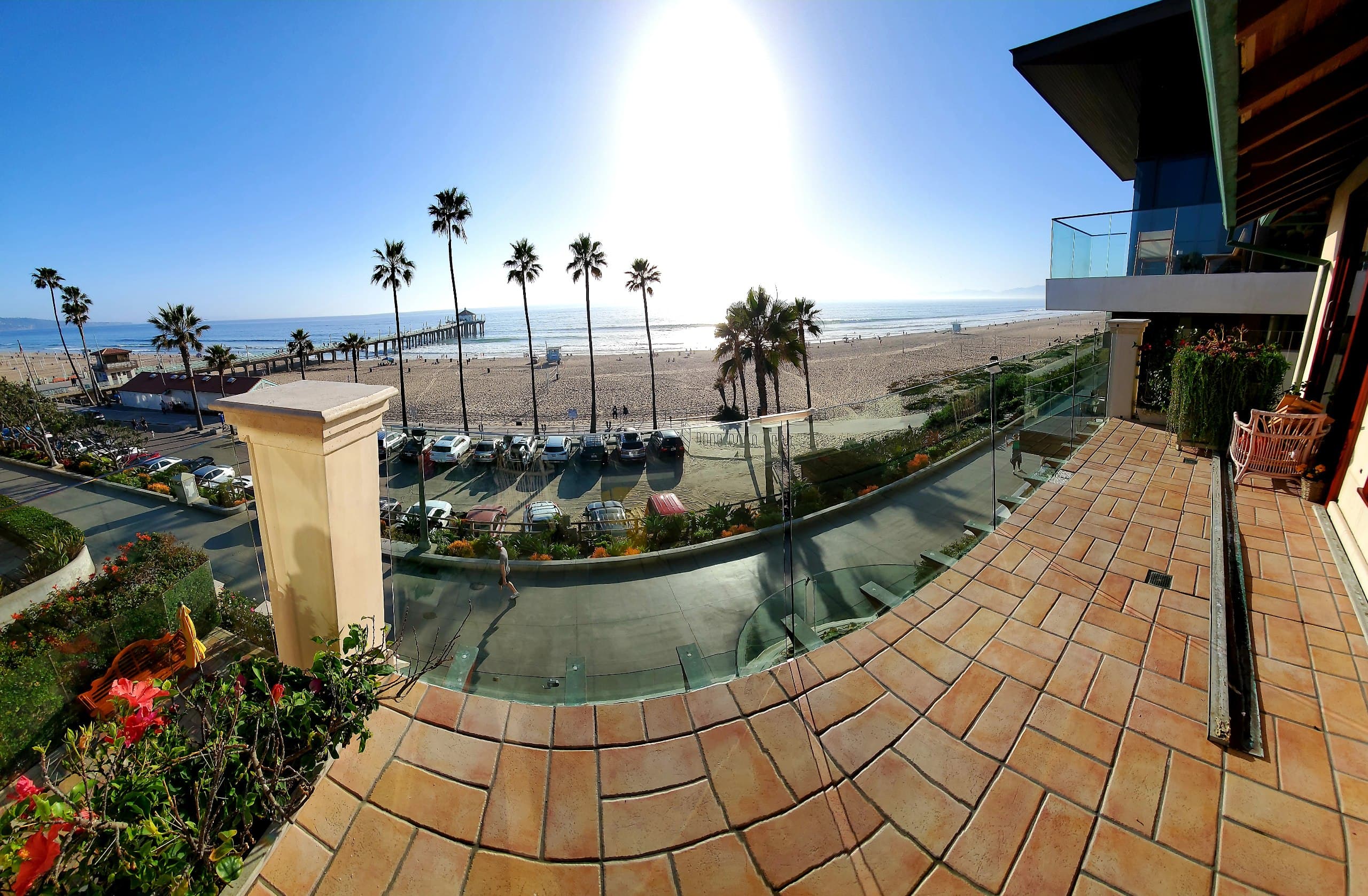 Curved frameless glass balcony railing on a terrace overlooking the pier, the sand and the ocean