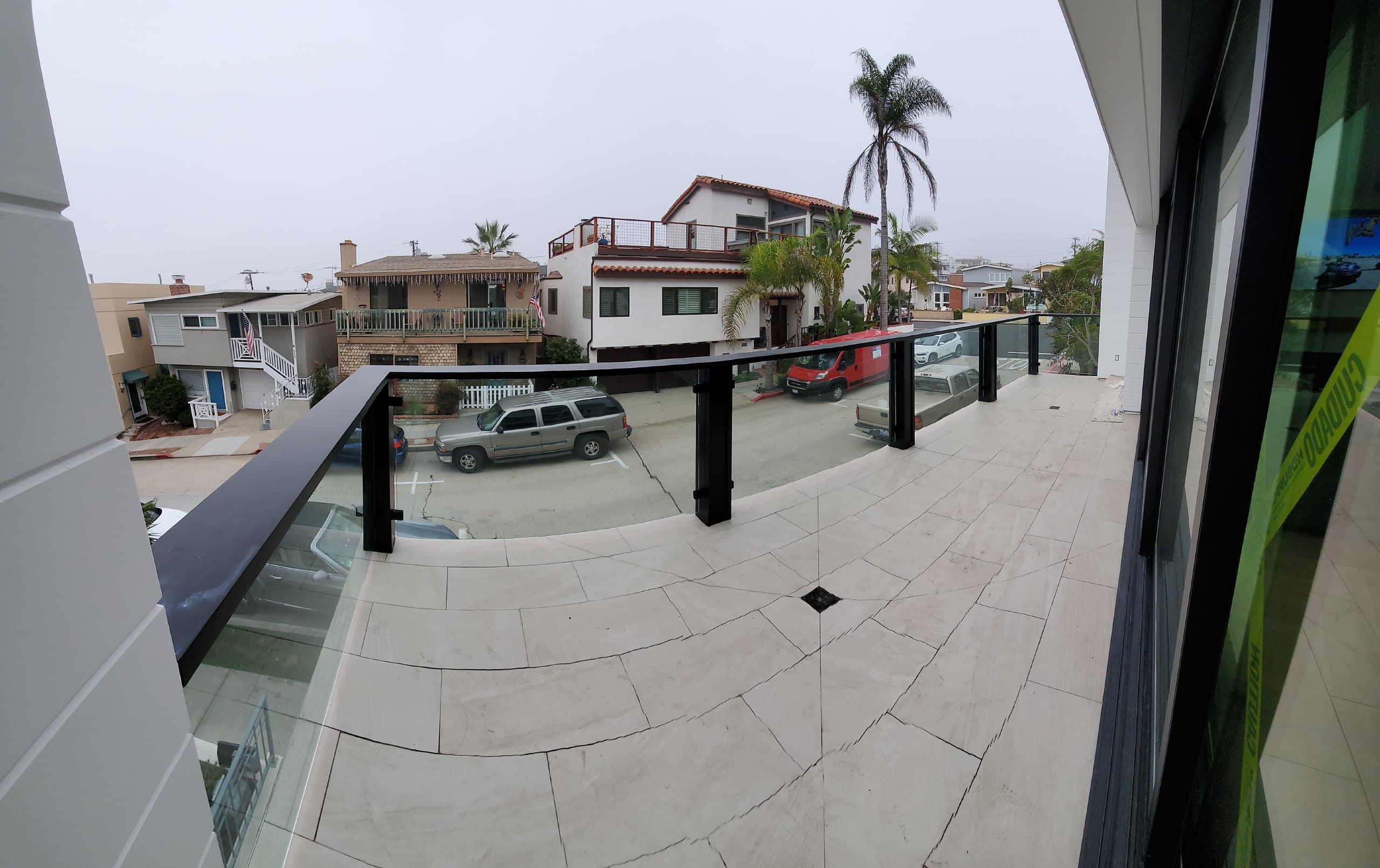 Glass balcony railing with black posts and cap rail on a beach-house terrace
